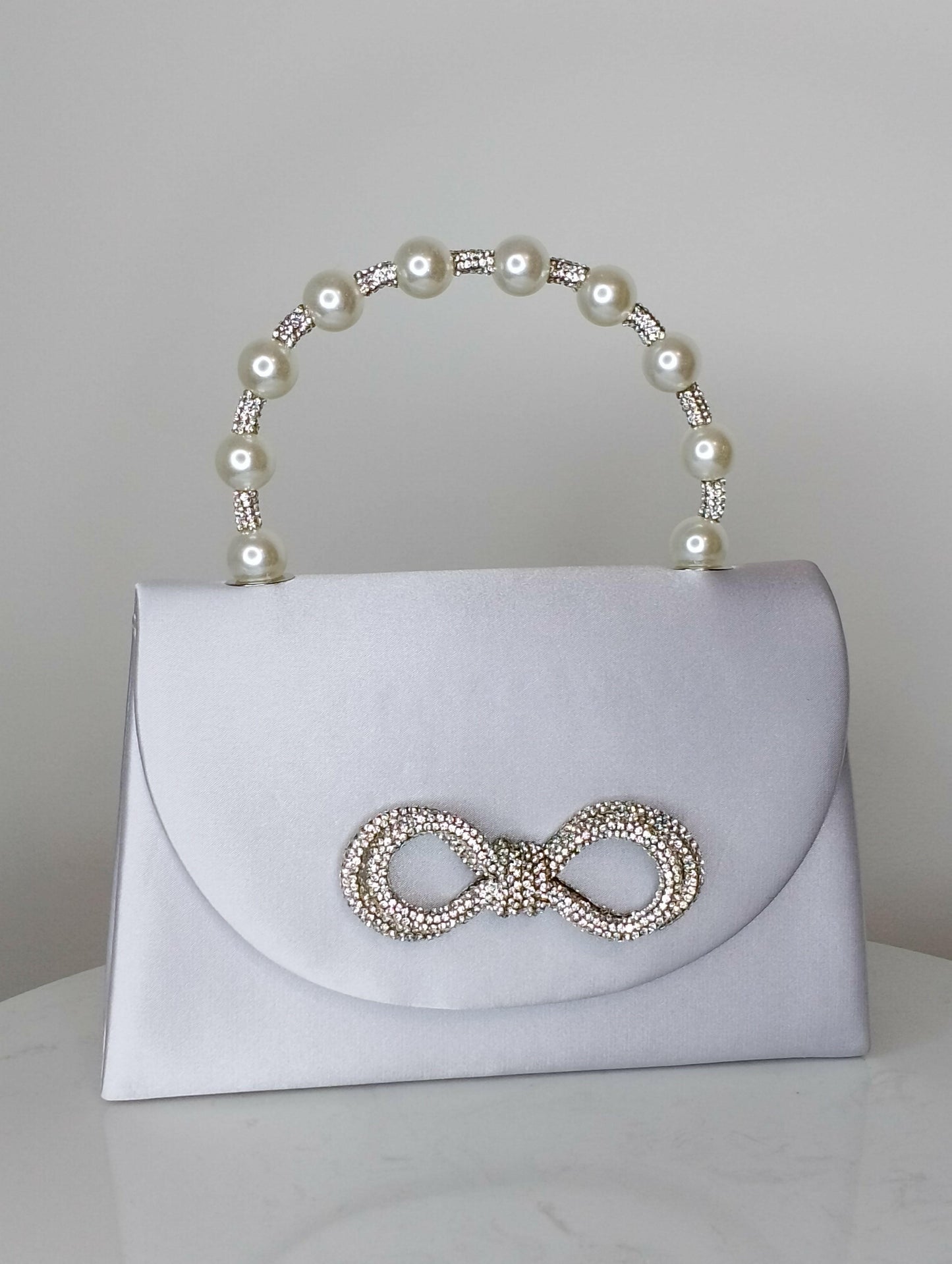Sac Perla design sophistiqué, vue portée - sac chic noir ou gris avec nœud strass décoratif pour cérémonies et mariages