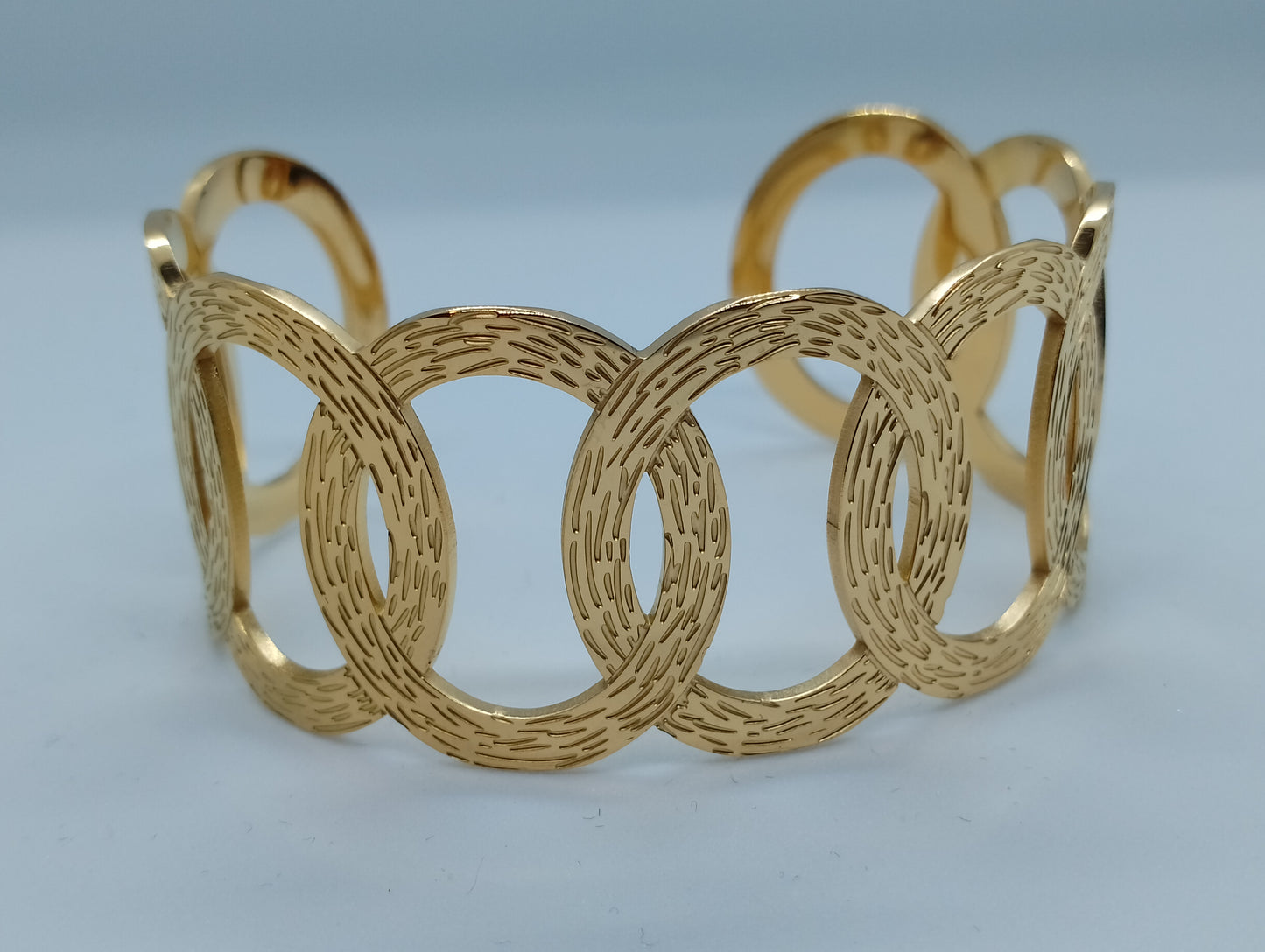 Bracelet Gaïa acier inoxydable doré cercles entrelacés, vue de face - bracelet largeur 6,5cm style unique pour occasions formelles et informelles