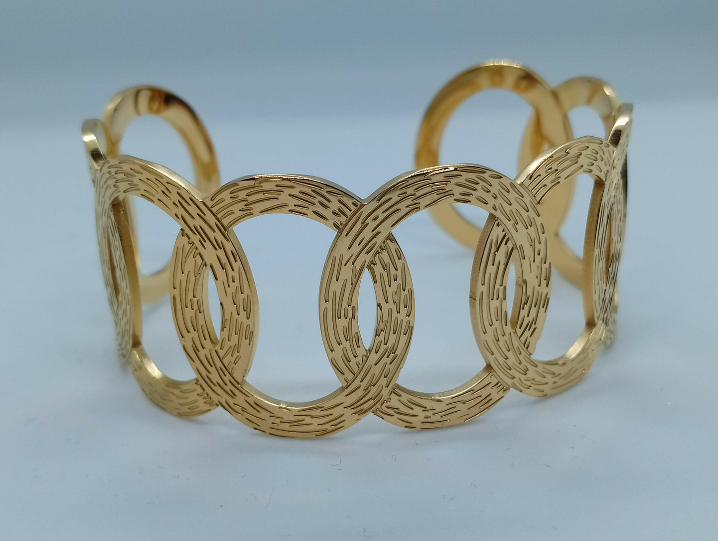 Bracelet Gaïa acier inoxydable doré cercles entrelacés, vue de face - bracelet largeur 6,5cm style unique pour occasions formelles et informelles