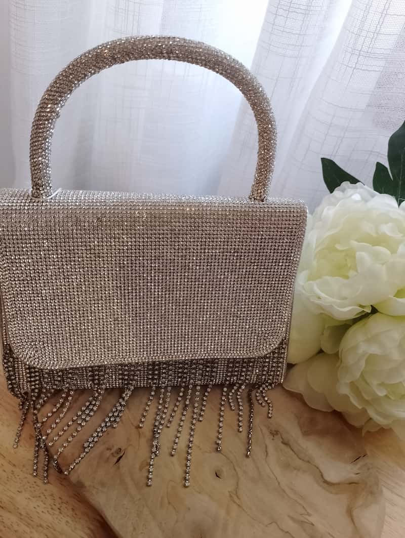 Sac Félicia pochette argentée strass franges, posé sur bois avec fleurs blanches, accessoire soirée BONITALUZ