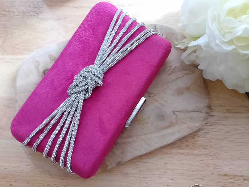 Sac Rosaria pochette velours fuchsia nœud sculptural chaînes argentées sur marbre blanc, sac soirée femme BONITALUZ