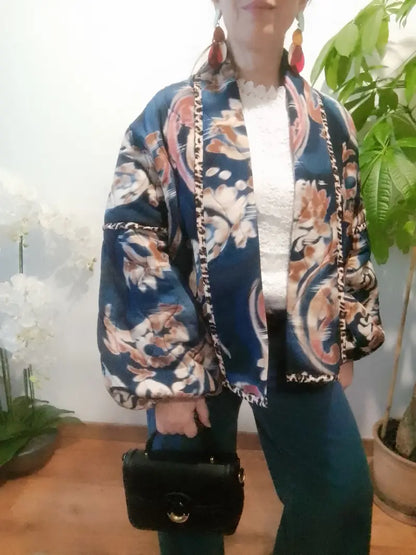 Veste fleurie portée ouverte sur un haut blanc, montrant sa coupe et ses manches amples. 