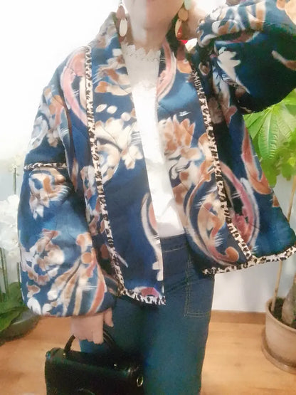 Détail des motifs floraux et des bordures décoratives de la veste bleu foncé portée ouverte