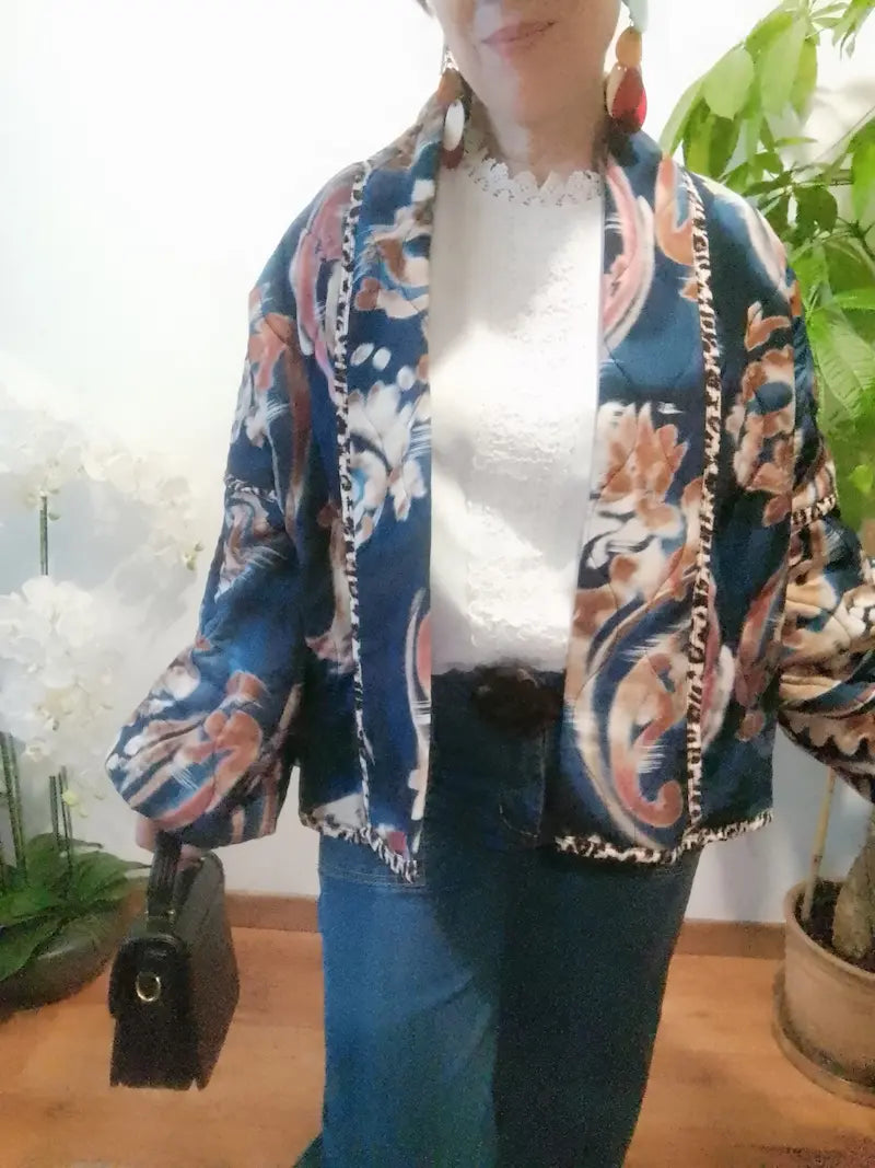 Veste bleu foncé à motifs floraux roses et crème, portée de face avec un jean et un sac noir.
